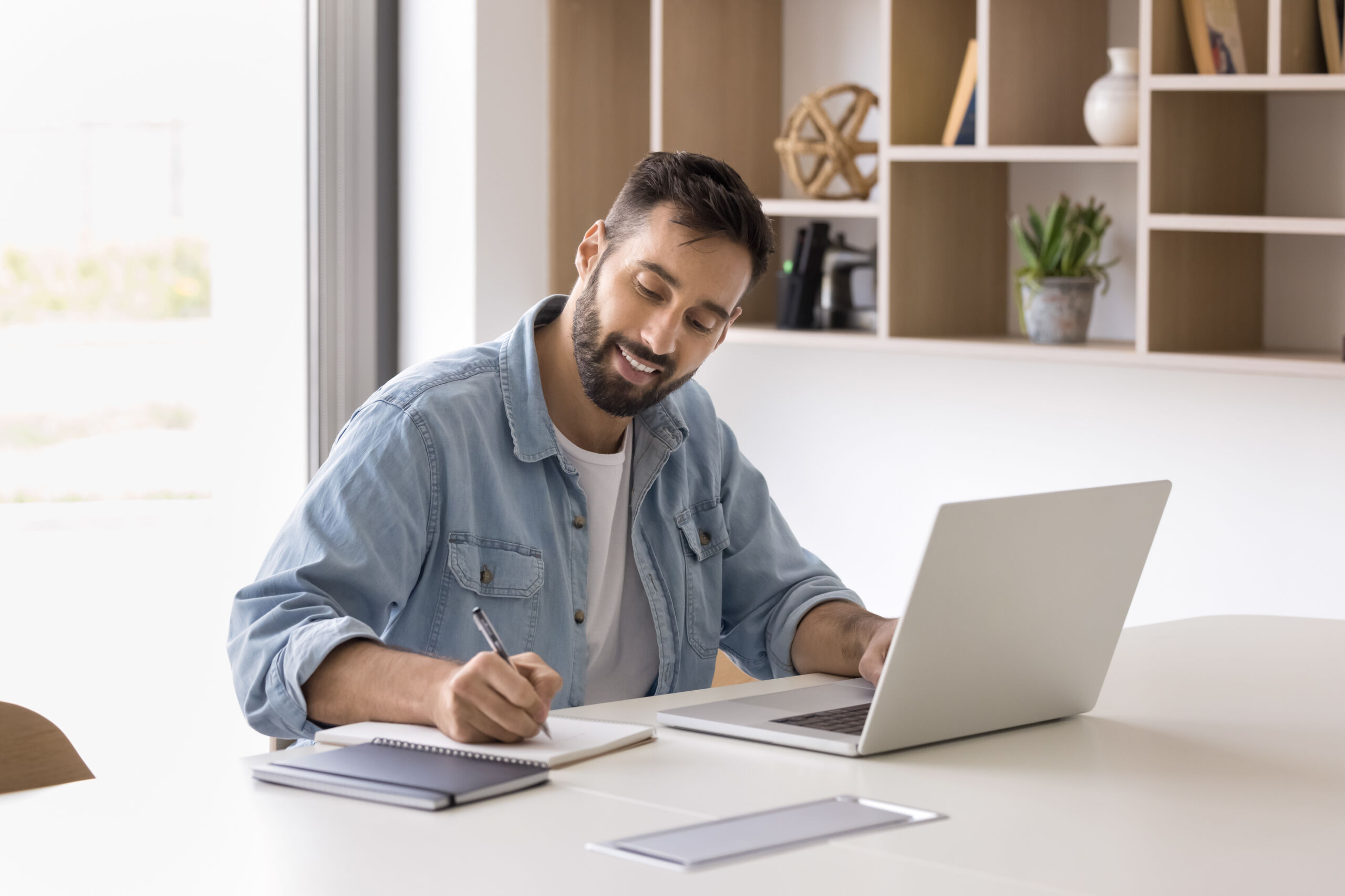 Positive Hispanic entrepreneur man using laptop for working in office